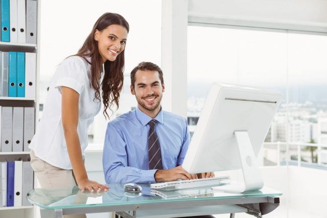 Photo of man and woman in office with computer illustrates blog "Cyber Liability Insurance: Who Needs It and Claim Examples"