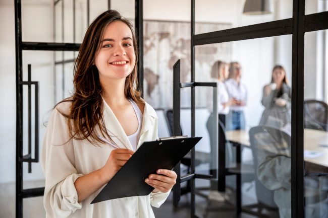 Professional woman holding clipboard illustrates blog "How Much Professional Liability Insurance Do I Need?"