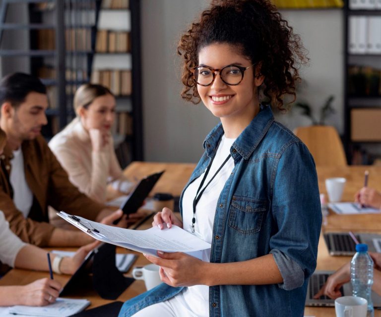 Professional woman smiling with meeting on the background illustrates blog "General Liability Insurance: What You Need To Know"