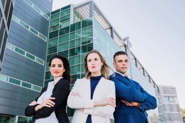 A man and two women in business attire outside a building illustrate blog "Why Do Companies Need Directors and Officers Insurance?"